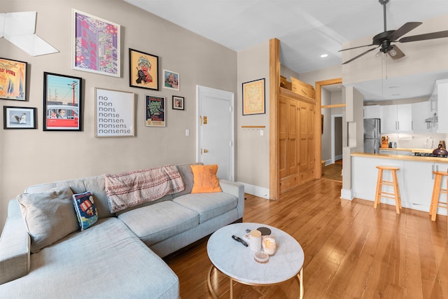 living room with a ceiling fan, baseboards, recessed lighting, and light wood-type flooring