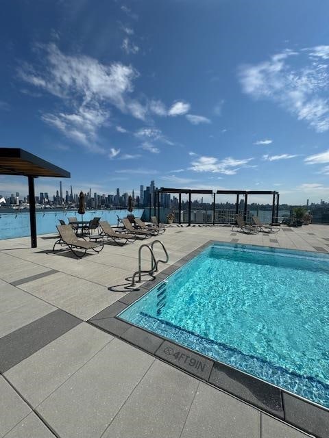 view of swimming pool with a patio area and a water view