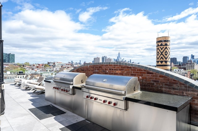 view of patio / terrace featuring a city view, exterior kitchen, and grilling area