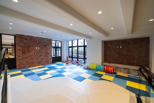 recreation room with beamed ceiling, carpet flooring, recessed lighting, and brick wall