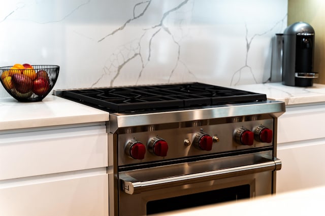 details with decorative backsplash, light stone countertops, and high end range
