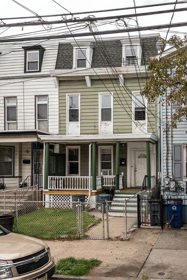 townhome / multi-family property featuring a fenced front yard, mansard roof, a gate, a porch, and a shingled roof