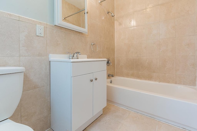 full bathroom featuring toilet, vanity, tub / shower combination, and tile walls