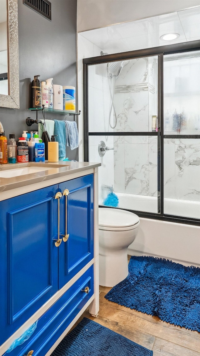 2212 Grand Ave, North Bergen, NJ 07047 - bathroom featuring vanity, toilet, wood finished floors, and combined bath / shower with glass door