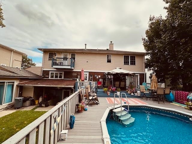 rear view of house featuring a pool side deck and a balcony