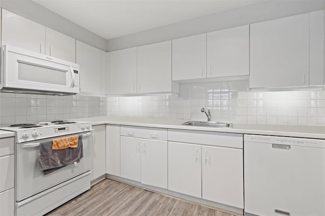 kitchen featuring decorative backsplash, light countertops, light wood finished floors, white appliances, and a sink