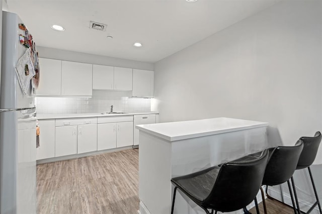 kitchen featuring freestanding refrigerator, light countertops, a sink, and visible vents