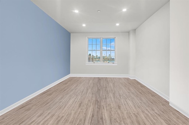 empty room featuring baseboards, wood finished floors, and recessed lighting