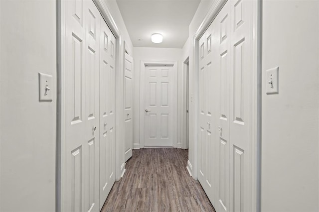 corridor with baseboards and dark wood-type flooring