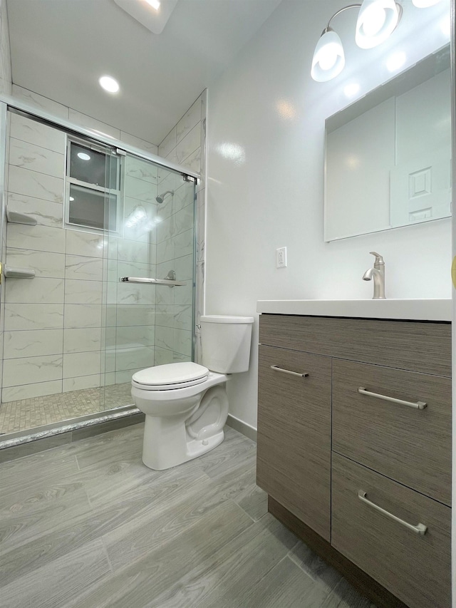 bathroom with a shower with door, vanity, and toilet