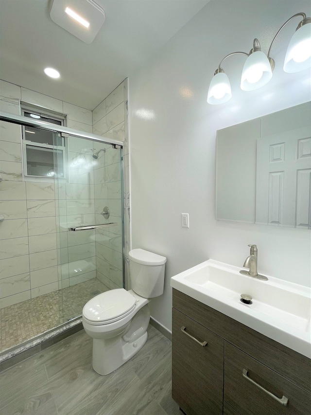 bathroom with hardwood / wood-style floors, vanity, an enclosed shower, and toilet