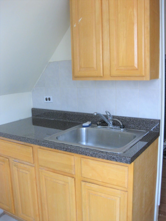 kitchen featuring light brown cabinetry, backsplash, vaulted ceiling, and sink