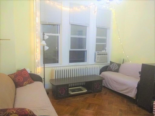 interior space with dark parquet floors, cooling unit, radiator heating unit, and an inviting chandelier