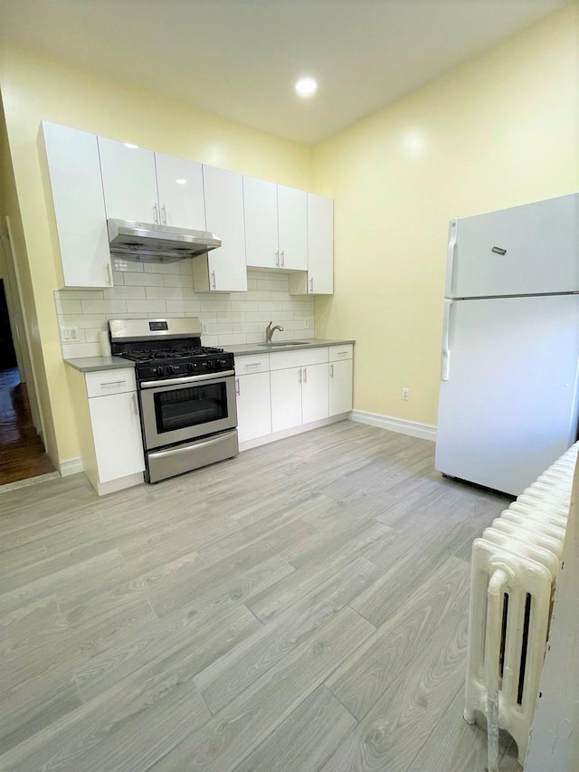 kitchen featuring white cabinets, white refrigerator, sink, gas range, and light wood-type flooring