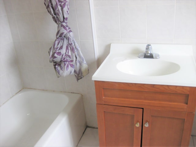 bathroom featuring vanity, a bathtub, and tile walls