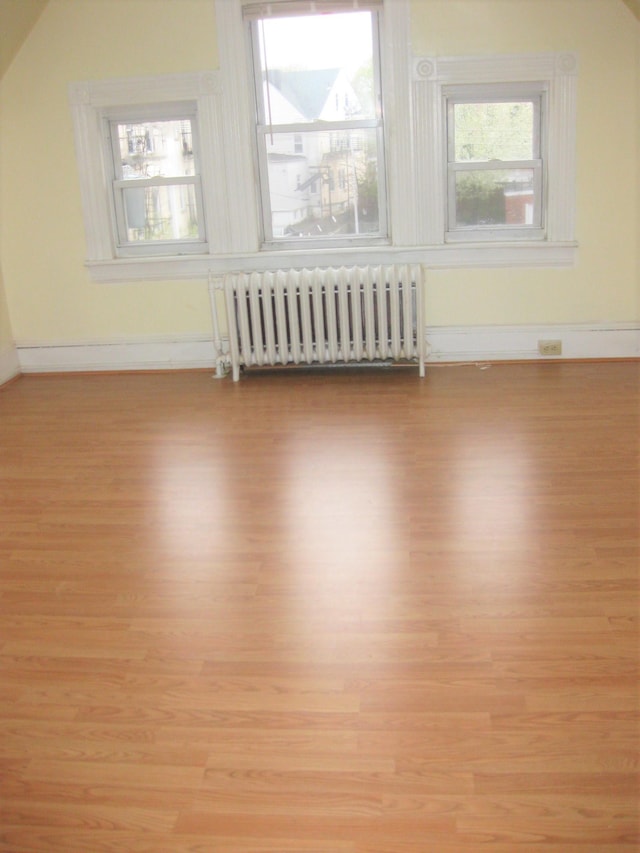 bonus room with radiator and light wood-type flooring