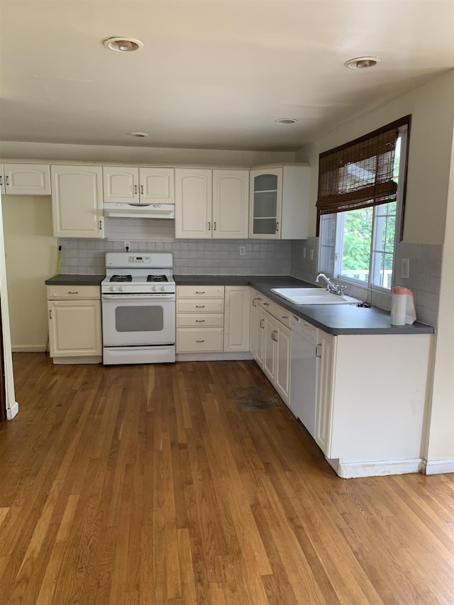 kitchen with white cabinetry, sink, backsplash, hardwood / wood-style flooring, and white appliances