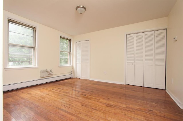 330 2nd St, Jersey City, NJ 07302 - unfurnished bedroom featuring a baseboard radiator, two closets, wood finished floors, and baseboards