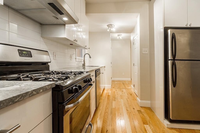 330 2nd St, Jersey City, NJ 07302 - kitchen with stainless steel appliances, a sink, light wood-style floors, white cabinetry, and baseboards