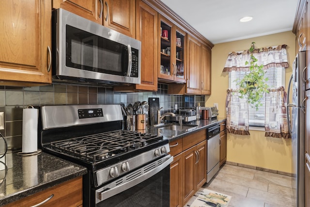12 Egan Ct, Bayonne, NJ 07002 - kitchen featuring appliances with stainless steel finishes, brown cabinets, dark stone countertops, decorative backsplash, and glass insert cabinets