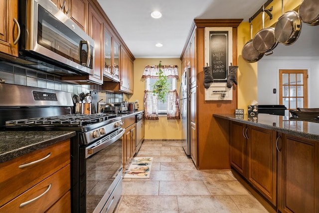 12 Egan Ct, Bayonne, NJ 07002 - kitchen featuring appliances with stainless steel finishes, crown molding, brown cabinetry, glass insert cabinets, and dark stone counters