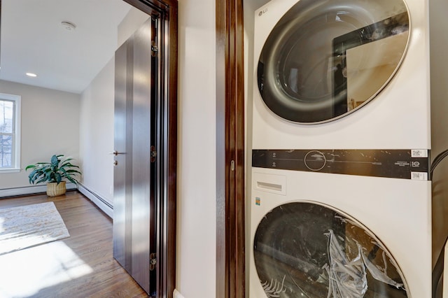 clothes washing area with stacked washing maching and dryer and light wood-type flooring