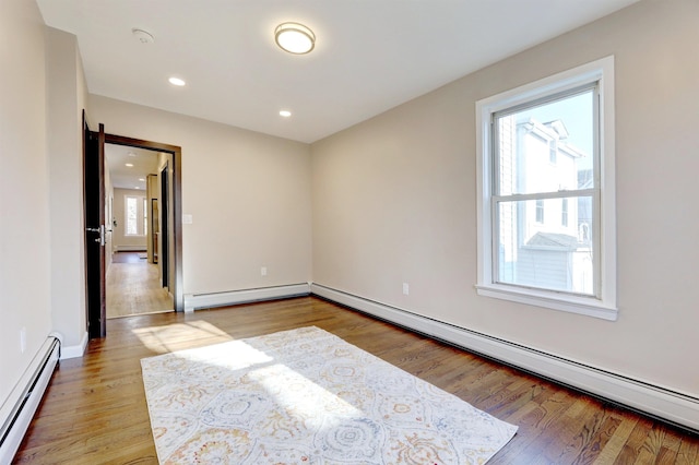 empty room featuring hardwood / wood-style flooring and a baseboard heating unit