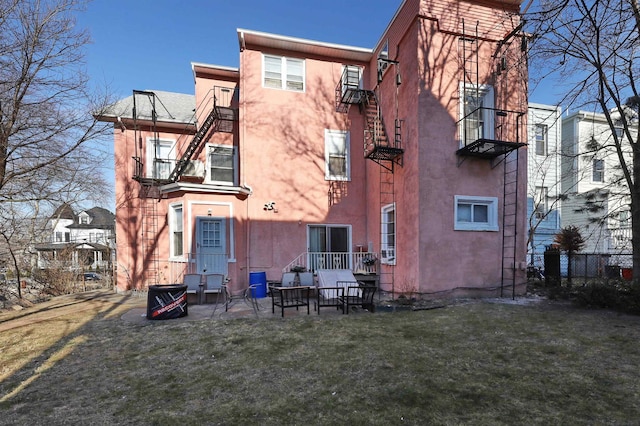 rear view of property featuring a patio, a balcony, and a lawn