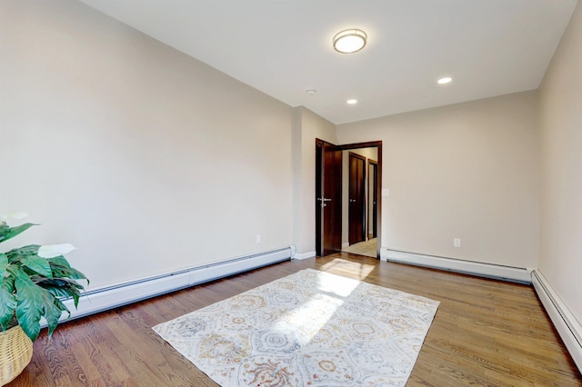 unfurnished room with a baseboard heating unit and hardwood / wood-style floors