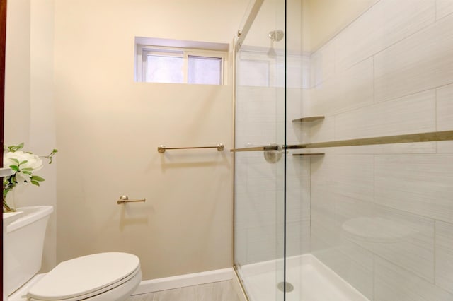 bathroom featuring a shower with shower door and toilet