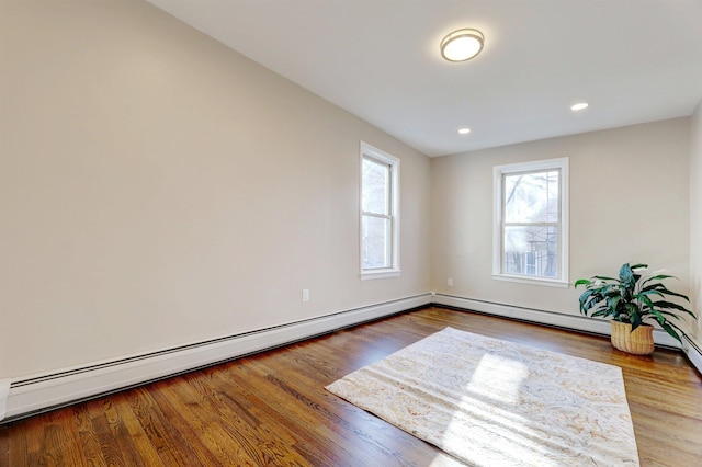 empty room featuring a baseboard heating unit and wood-type flooring