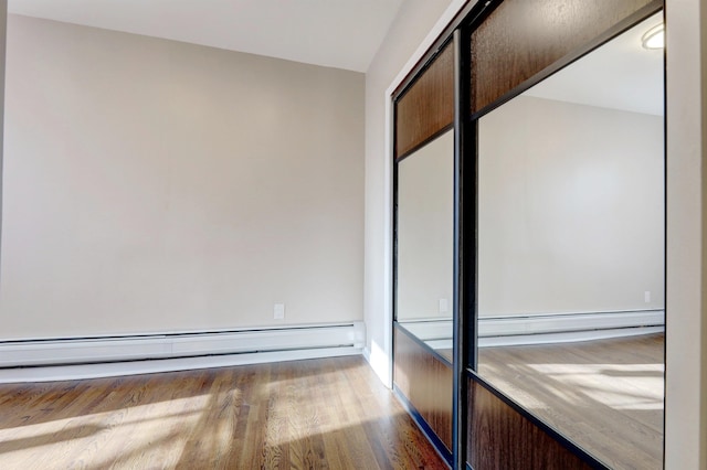 unfurnished bedroom featuring hardwood / wood-style flooring and a baseboard radiator