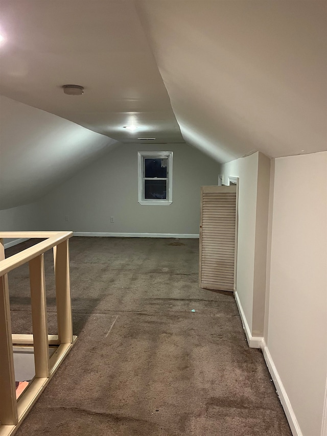 bonus room featuring dark colored carpet and lofted ceiling