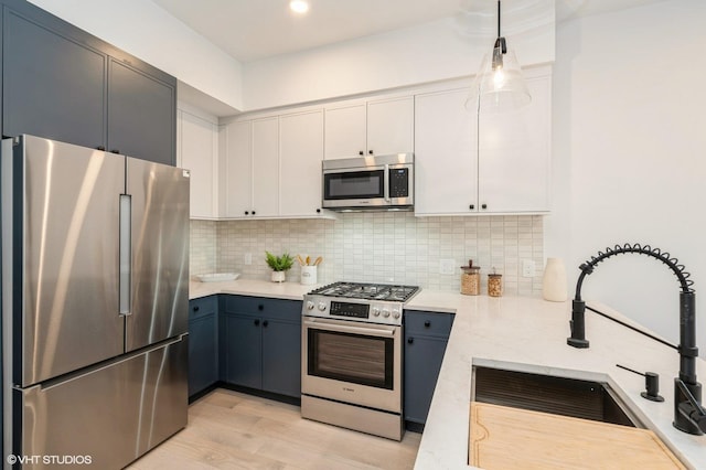 425 3rd St Unit 318, Jersey City, NJ 07302 - kitchen with stainless steel appliances, a sink, decorative backsplash, light wood finished floors, and white cabinets