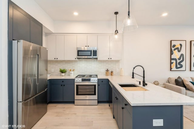 425 3rd St Unit 318, Jersey City, NJ 07302 - kitchen with appliances with stainless steel finishes, a sink, a peninsula, light wood finished floors, and backsplash