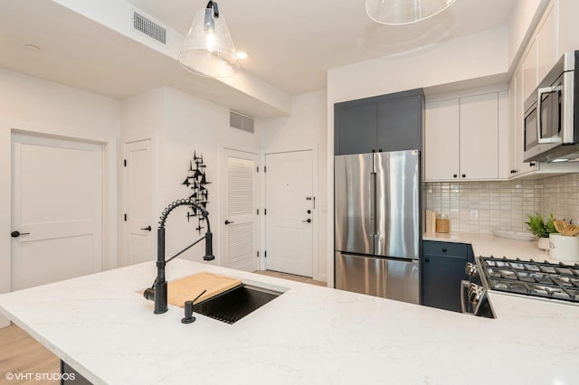 425 3rd St Unit 318, Jersey City, NJ 07302 - kitchen with appliances with stainless steel finishes, decorative backsplash, light stone countertops, pendant lighting, and a sink