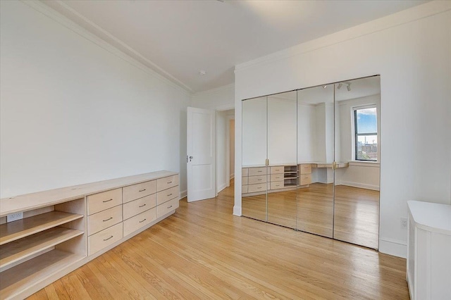 unfurnished bedroom with light wood-type flooring, ornamental molding, and a closet