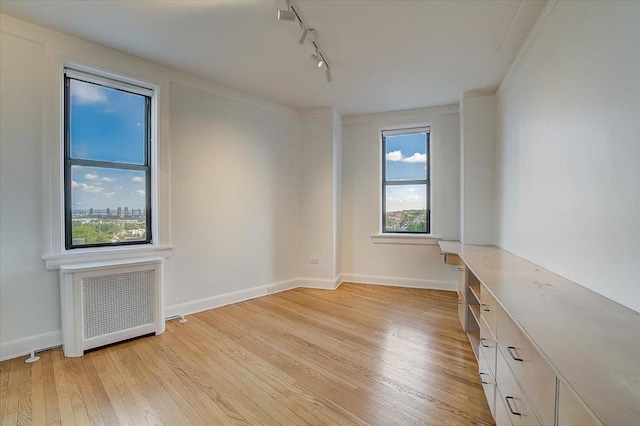 unfurnished room with radiator, a wealth of natural light, and light hardwood / wood-style flooring