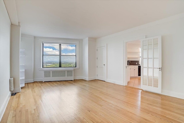 spare room featuring radiator heating unit and light wood-type flooring