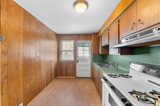 11 Veterans Ct, Bayonne, NJ 07002 - kitchen with gas range gas stove, light wood-style floors, brown cabinetry, under cabinet range hood, and wood walls