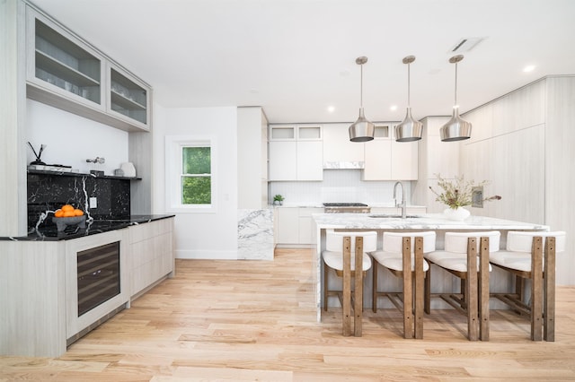 90 Monroe St Unit 2, Hoboken, NJ 07030 - kitchen featuring a kitchen breakfast bar, a sink, light wood finished floors, decorative backsplash, and glass insert cabinets