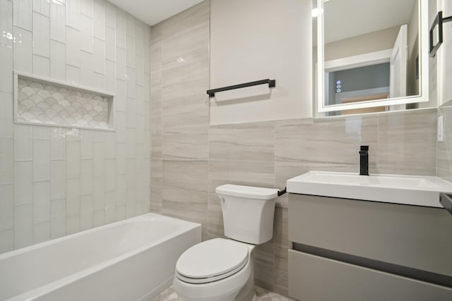 full bathroom featuring vanity, toilet, tiled shower / bath combo, and tile walls