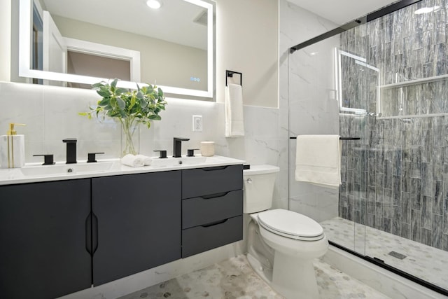 bathroom with vanity, toilet, a shower with shower door, and tile walls