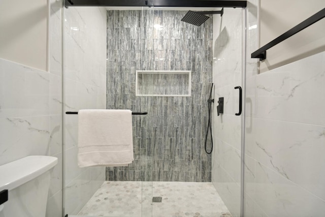 bathroom with tile walls, an enclosed shower, and toilet