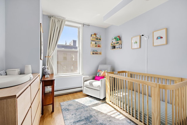 118 Clinton St Unit 7, Hoboken, NJ 07030 - bedroom with baseboard heating, light wood-type flooring, and a nursery area