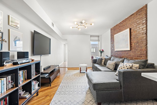 118 Clinton St Unit 7, Hoboken, NJ 07030 - living room with light wood finished floors, a chandelier, baseboards, and brick wall