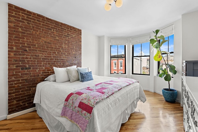 118 Clinton St Unit 7, Hoboken, NJ 07030 - bedroom with brick wall, baseboards, and light wood finished floors