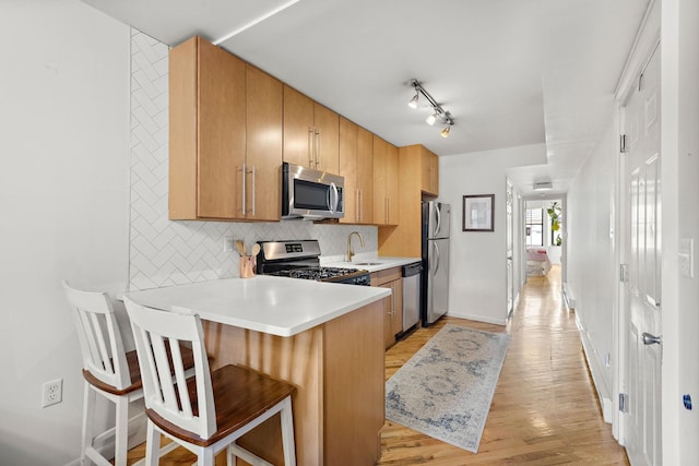 118 Clinton St Unit 7, Hoboken, NJ 07030 - kitchen with appliances with stainless steel finishes, a sink, tasteful backsplash, a breakfast bar, and light wood-type flooring
