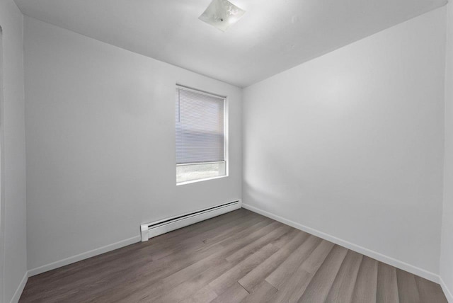 unfurnished room featuring hardwood / wood-style flooring and a baseboard heating unit