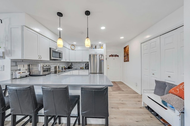 539 Bayway Cir Unit 2C, Elizabeth, NJ 07202 - kitchen featuring stainless steel appliances, a peninsula, white cabinetry, light wood-style floors, and recessed lighting